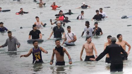 Un grupo de inmigrantes en la playa junto al paso fronterizo del Tarajal en Ceuta