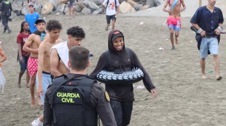 Un grupo de inmigrantes en la playa junto al paso fronterizo del Tarajal en Ceuta este viernes,