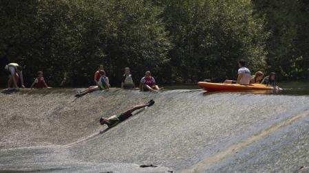 Varias personas se refrescan en el río Arga, en Pamplona