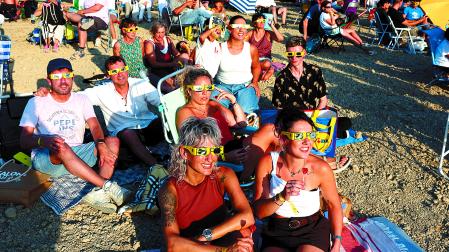 Sentados en sillas o en el suelo, esperando la llegada del eclipse en el antiguo campo de fútbol de La Valdechate de Lerín