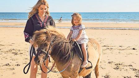 Nerea Berraondo en la playa de Matalascañas junto a su hija Sara, de 4 años, a lomos del poni Barbas