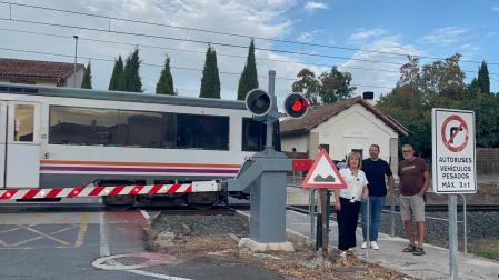Mari Carmen Tirapu, Óscar Amóztegui e Iñaki Martínez posan junto al paso a nivel mientras circula un tren de pasajeros por Esquíroz.