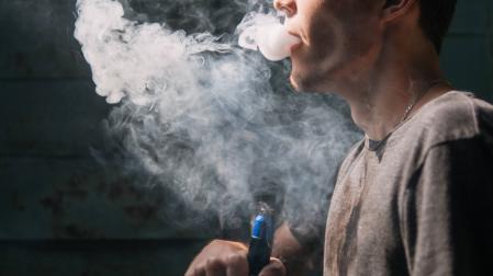 Un joven fuma un cigarrillo electrónico