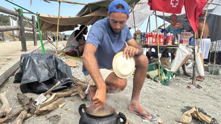 Varios inmigrantes se preparan la comida este miércoles en la playa del Trampolín