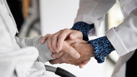 Una persona voluntaria da la mano a un paciente.
