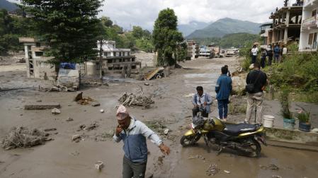 Varias personas caminan por las calles inundadas en Trishuli Bazar, en el distrito de Nuwakot