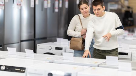 Dos jóvenes comparan electrodomésticos en una tienda outlet