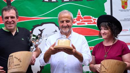 Enirque Martínez, del restaurante Maher, sujeta el queso ganador entre los representantes de la quesería Loperena, ganadores del concurso.
