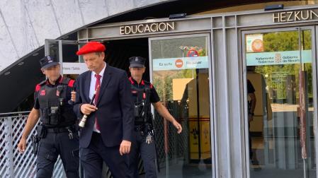 Ricardo Oficialdegui, con vestido de gaitero y con el instrumento en la mano, abandona la sede de Educación acompañado de dos agentes de la Policía Foral
