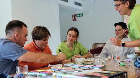 Xabier Carrascón Erice acompaña a su madre, María Josefa, en un ejercicio manual en presencia de la directora y trabajadora del Centro de Día ‘Txokolatero’, Amaia Lakarta Aizkorbe; la cocinera, Maitane Iribarren Ciáurriz; y la gerocultora, Marta Zubieta Ripalda.