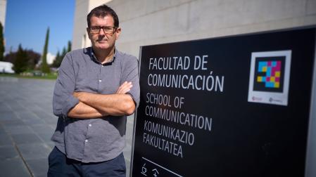 Pablo Echart se apoya en un cartel junto a la Facultad de Comunicación de la Universidad de Navarra.