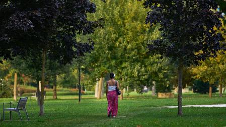 Una mujer pasea por una zona ajardinada de Pamplona