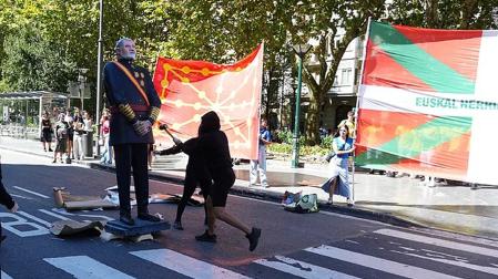 Varios manifestantes encapuchados derriban una estatua del Rey Felipe VI