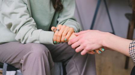 Una persona adulta tiende la mano a una joven.