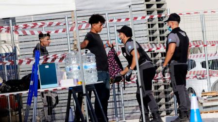 Inmigrantes acceden por el control y registro para de acceder al campamento temporal en muelle Poniente del puerto de Ceuta,