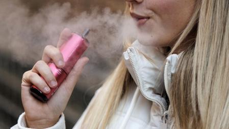 Una joven vapea humo con sabor melón y kiwi