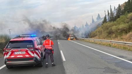 Una patrulla de la Policía Foral junto al coche ardiendo en la AP-15