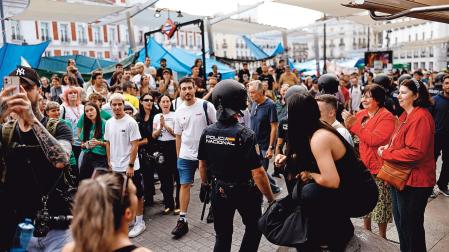 Un agente pasa entre los acampados en Sol, que continuarán la protesta pese al ultimátum de la presidenta de la Comunidad de Madrid