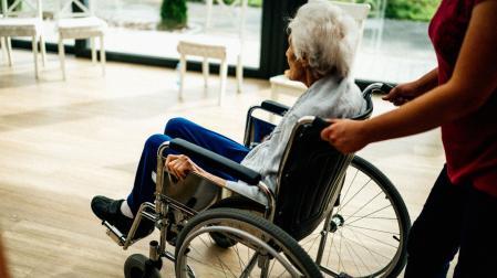 Cuidadora con anciana en silla de ruedas.