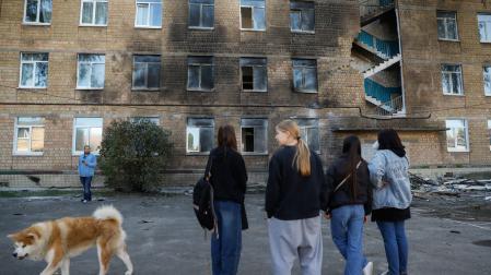 Varias estudiantes observan los daños en un edificio en Kiev resultado del ataque ruso de hace uno días