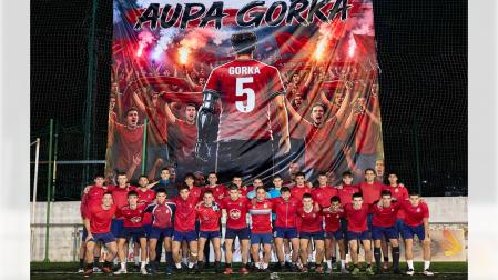La plantilla y el cuerpo técnico del Baztan posan delante de la pancarta en homenaje al joven Gorka Goñi