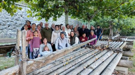 Vecinas y vecinos de Ezcároz vinculados al proyecto ‘Camino de agua y cuentos’ posan este viernes junto a la almadía que luce a orillas del río Salazar