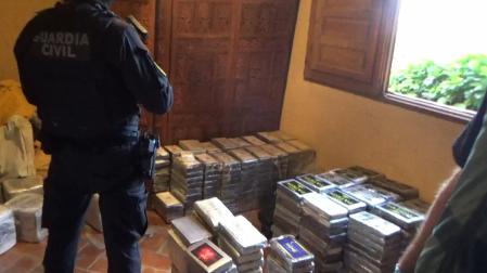 Un agente de la Guardia Civil junto a la droga incautada en la casa rural de Guadalajara