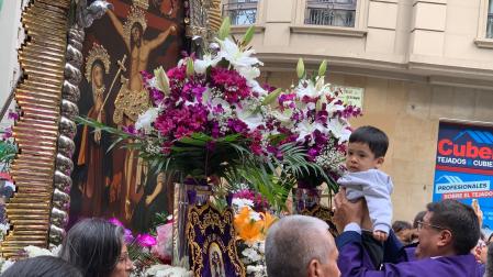 Un miembro de la hermandad acerca a un niño al Señor de los Milagros durante la procesión en la plaza de la Cruz de Pamplona