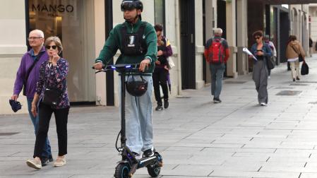 Un joven circula con su patinete eléctrico por una zona peatonal