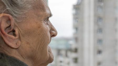 An elderly woman looking out the window