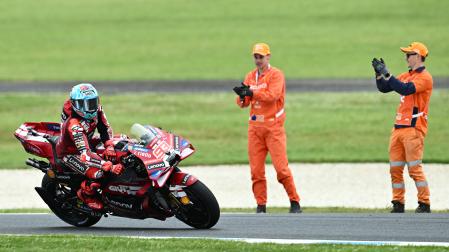 Dos empleados de Phillip Island aplauden a Marc Márquez tras su victoria en la carrera al sprint del GP de Australia