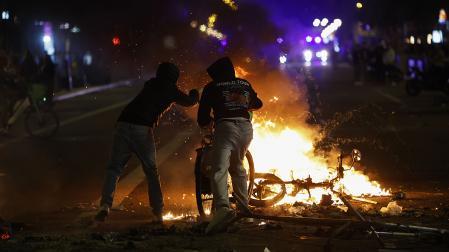 Dos estudiantes alimentan una hoguera durante las protestas de la pasada noche en Barcelona
