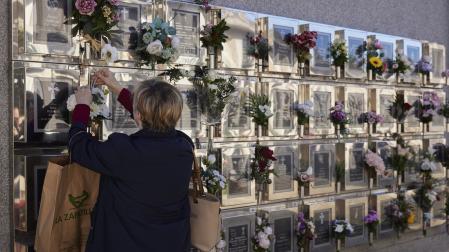 Una persona coloca flores en un columbario del cementerio de Pamplona. Contiene urnas cinerarias y son una opción en auge