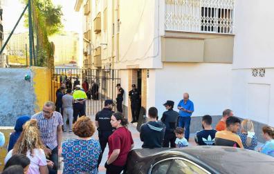 Vecinos de la barriada de Los Rosales y agentes de la Policía Nacional, a las afueras de la vivienda en la que ha tenido lugar el suceso.