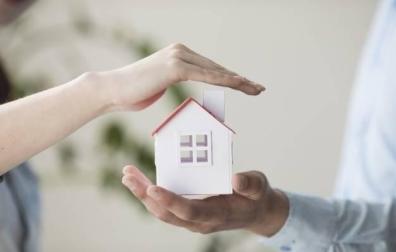 Imagen de unas manos y una casita en miniatura