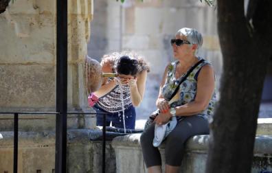 Una turista se refresca en una de las fuentes del patio de los Naranjos de la Mezquita-Catedral de Córdoba.