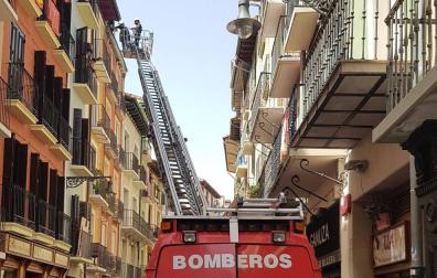 Los bomberos, durante la retirada del alero en mal estado en la calle San Antón.