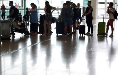 Varias personas esperan en el aeropuerto del Prat, Barcelona.