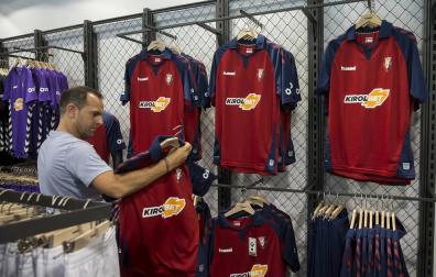 Un cliente examina la primera equipación de Osasuna, en la tienda de El Sadar, durante el verano.