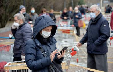 Personas con máscara hace cola en una supermercado en Italia.