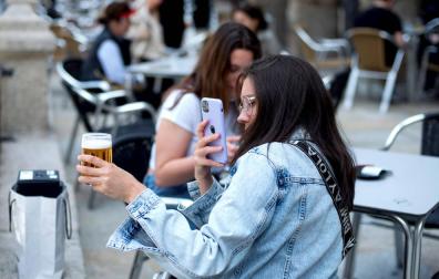 Una joven saca una fotografía a su cerveza en una terraza.