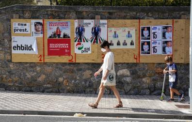Una mujer camina en Ordizia delante de unos carteles electorales.