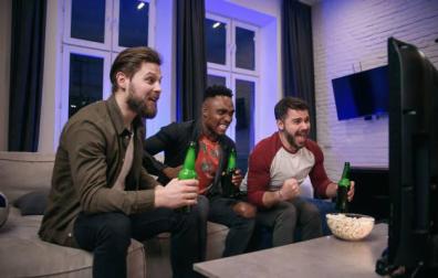 Tres amigos siguen un partido de la NBA por televisión