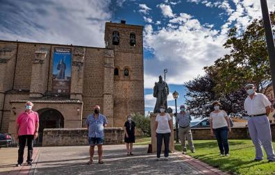 Algunos de los socios de la cofradía Amigos de San Veremundo en la entrada de la parroquia,  junto con la estatua del patrón de la localidad.