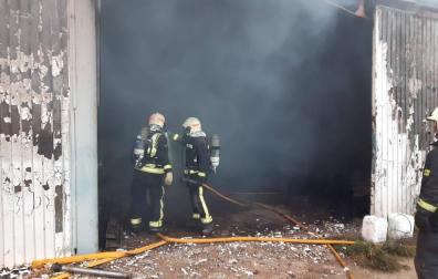 Dos bomberos, en la puerta de la nave que ha ardido.