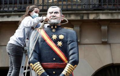 Una joven coloca una soga alrededor de la estatua de Felipe VI.