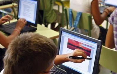 Varios niños utilizan ordenadores en un aula.