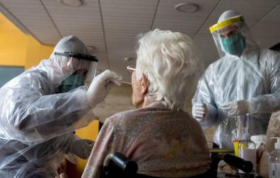 Varios sanitarios realizan la prueba del coronavirus a una anciana.