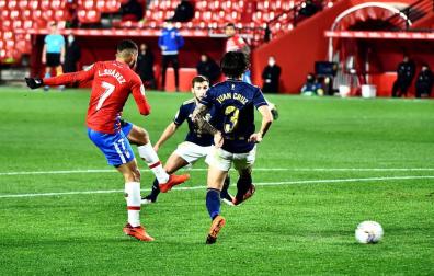 El delantero colombiano del Granada Luis Suárez golpea el balón ante dos rivales de Osasuna,