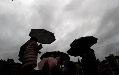 Un grupo de personas se protege con paraguas de la lluvia en Pamplona.